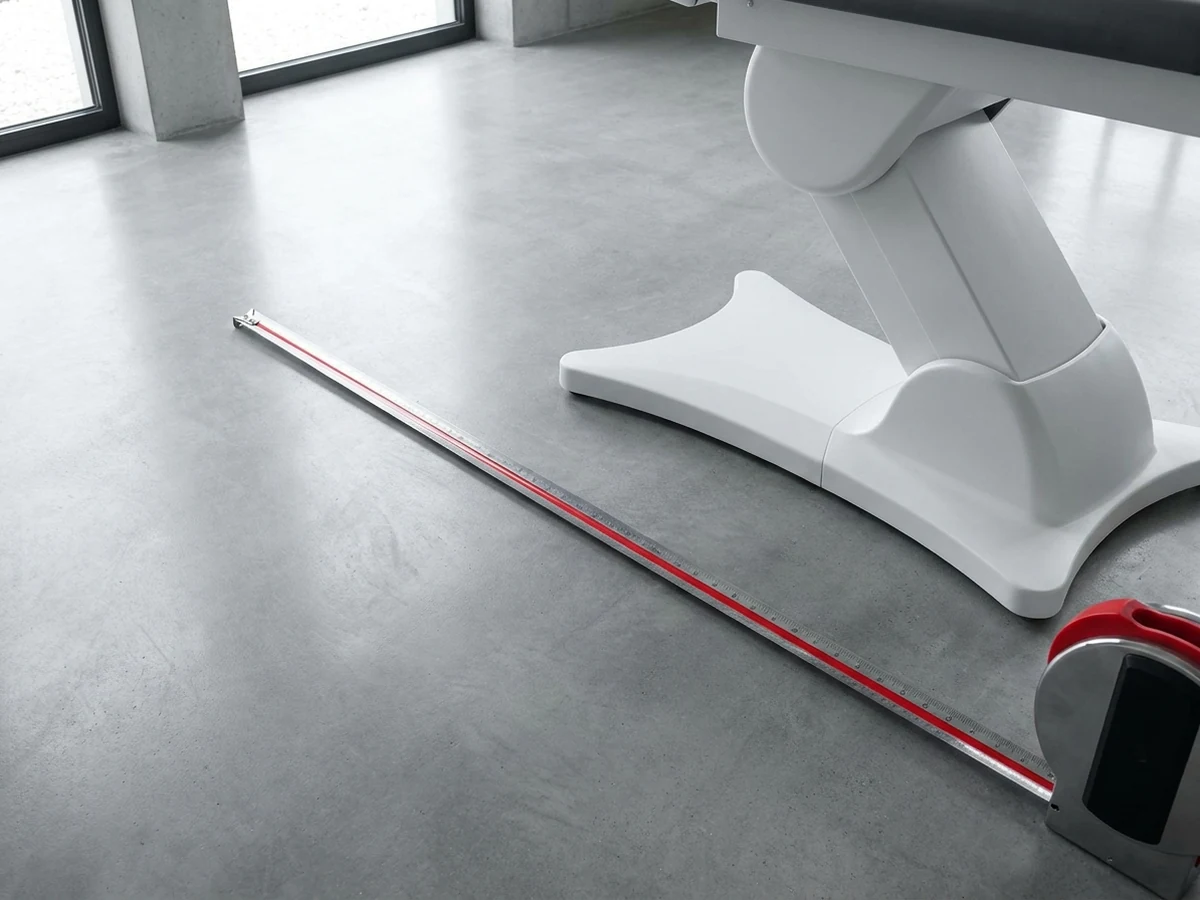 Cinta métrica sobre el piso de una sala de tratamiento junto a la base de una cama