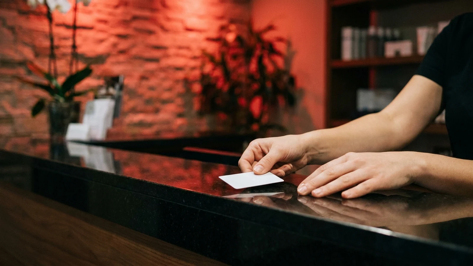 Recepción de un centro de bienestar entregando una tarjeta de membresía sobre el mostrador